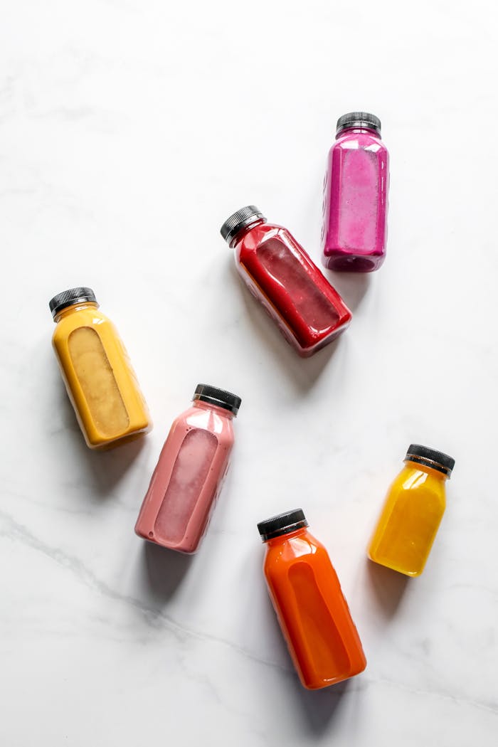 gallery-2 A vibrant array of healthy smoothies in bottles on a clean marble surface, perfect for a health-conscious lifestyle.