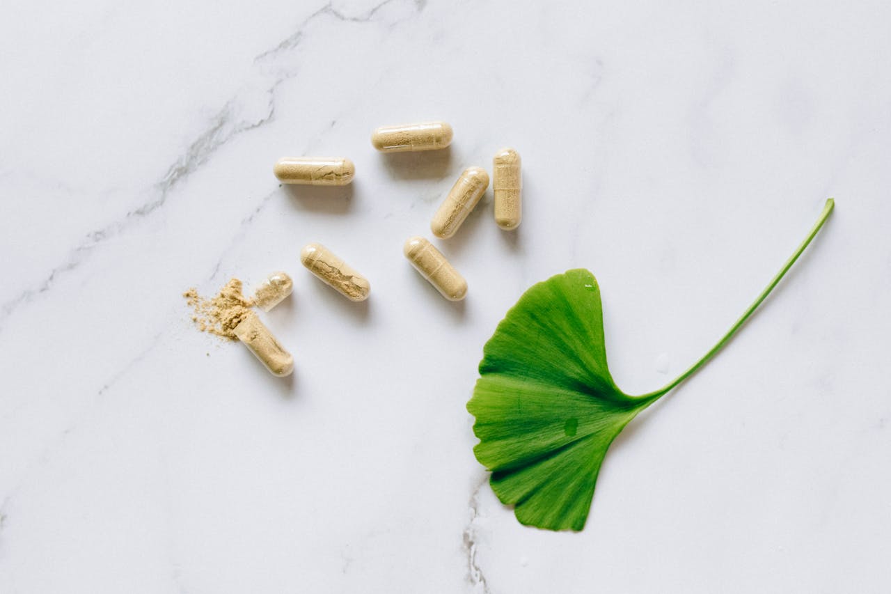 hero-img-01 Top view of Ginkgo Biloba capsules with a leaf on a marble surface, symbolizing natural supplements.